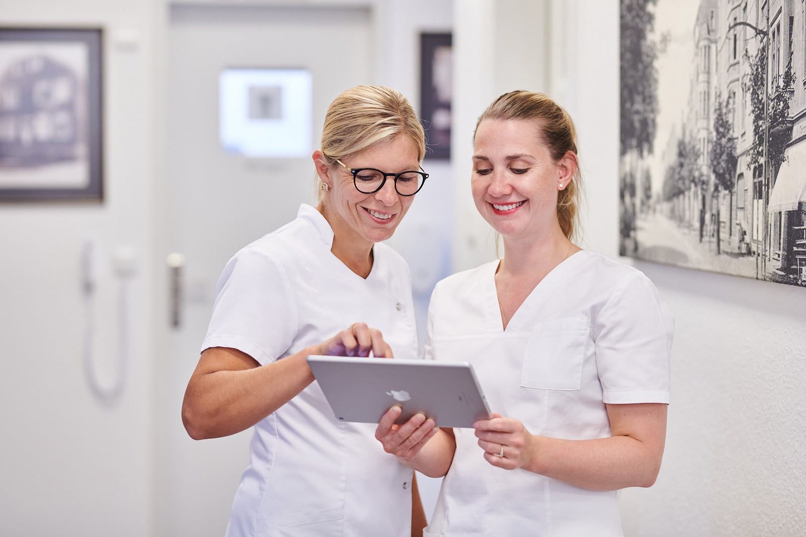 Portrait von Dr. Silke Schäfer und Dr. Sabrina Krüger im Flur besprechen Ergebnisse am Tablet